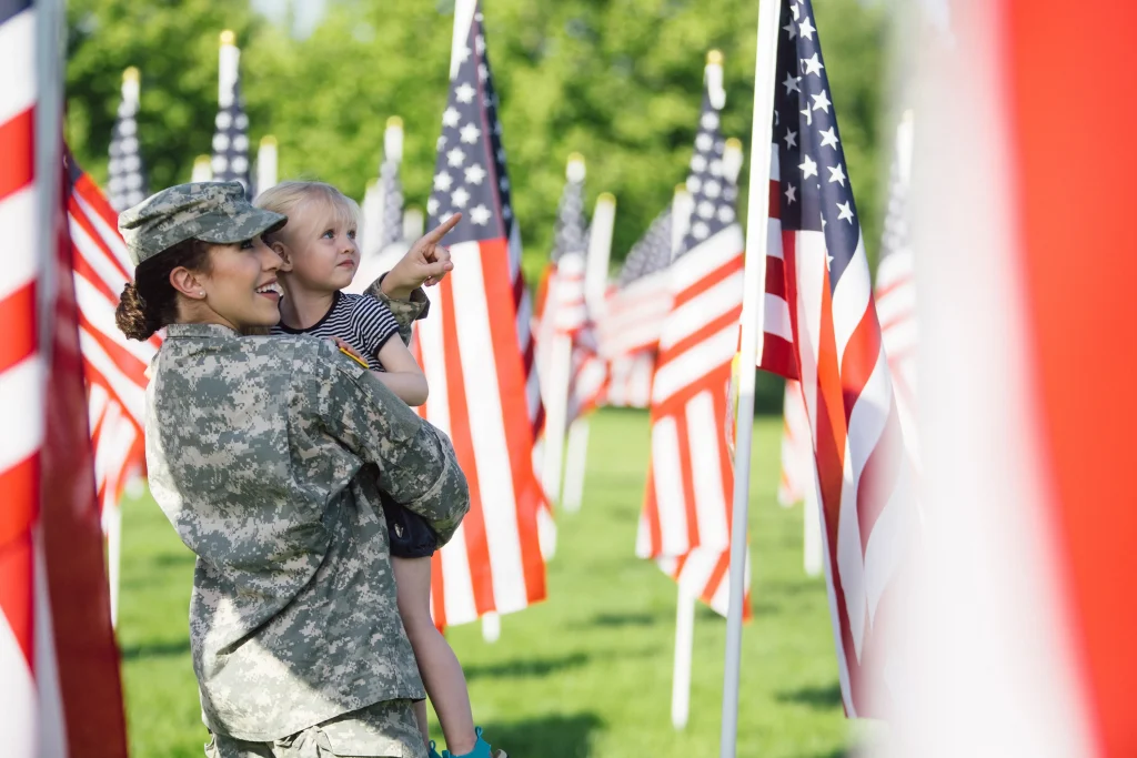 A soldier holding a child in a field of American flags
